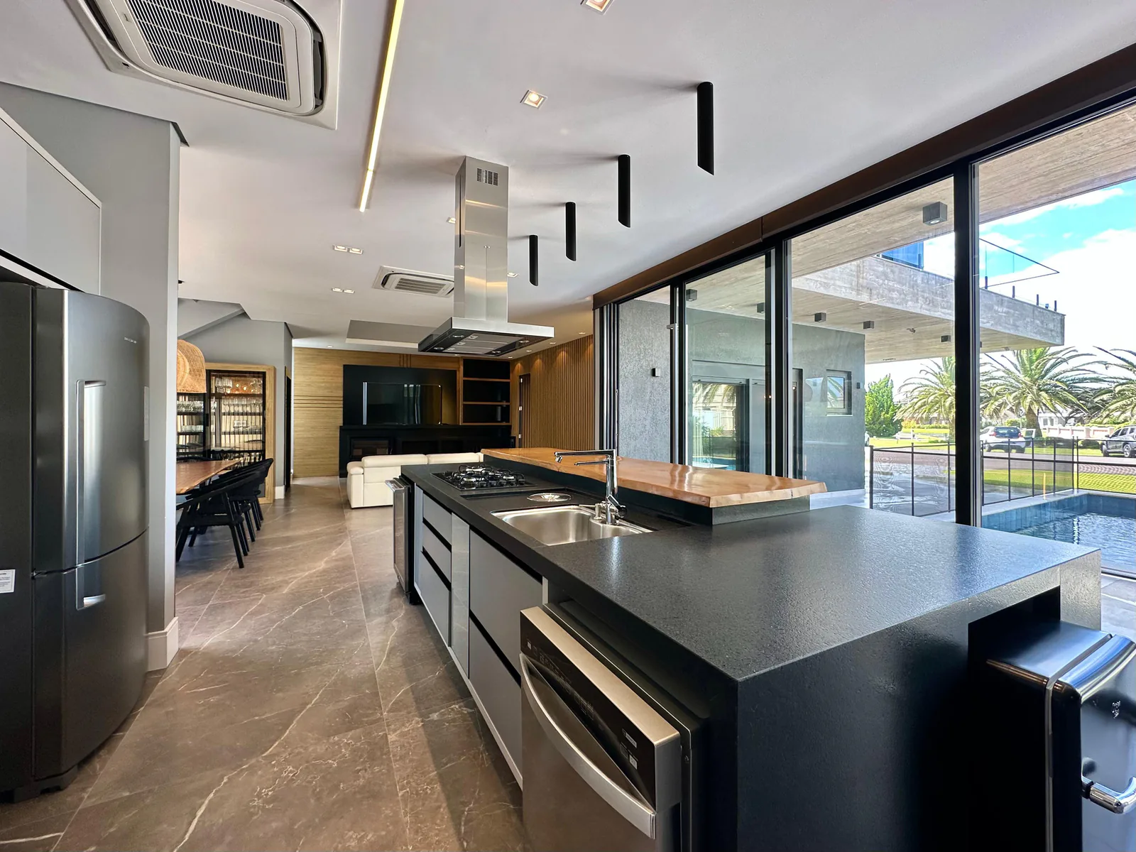 Cozinha e espaço gourmet integrados, com ilha central e abertura para a piscina
