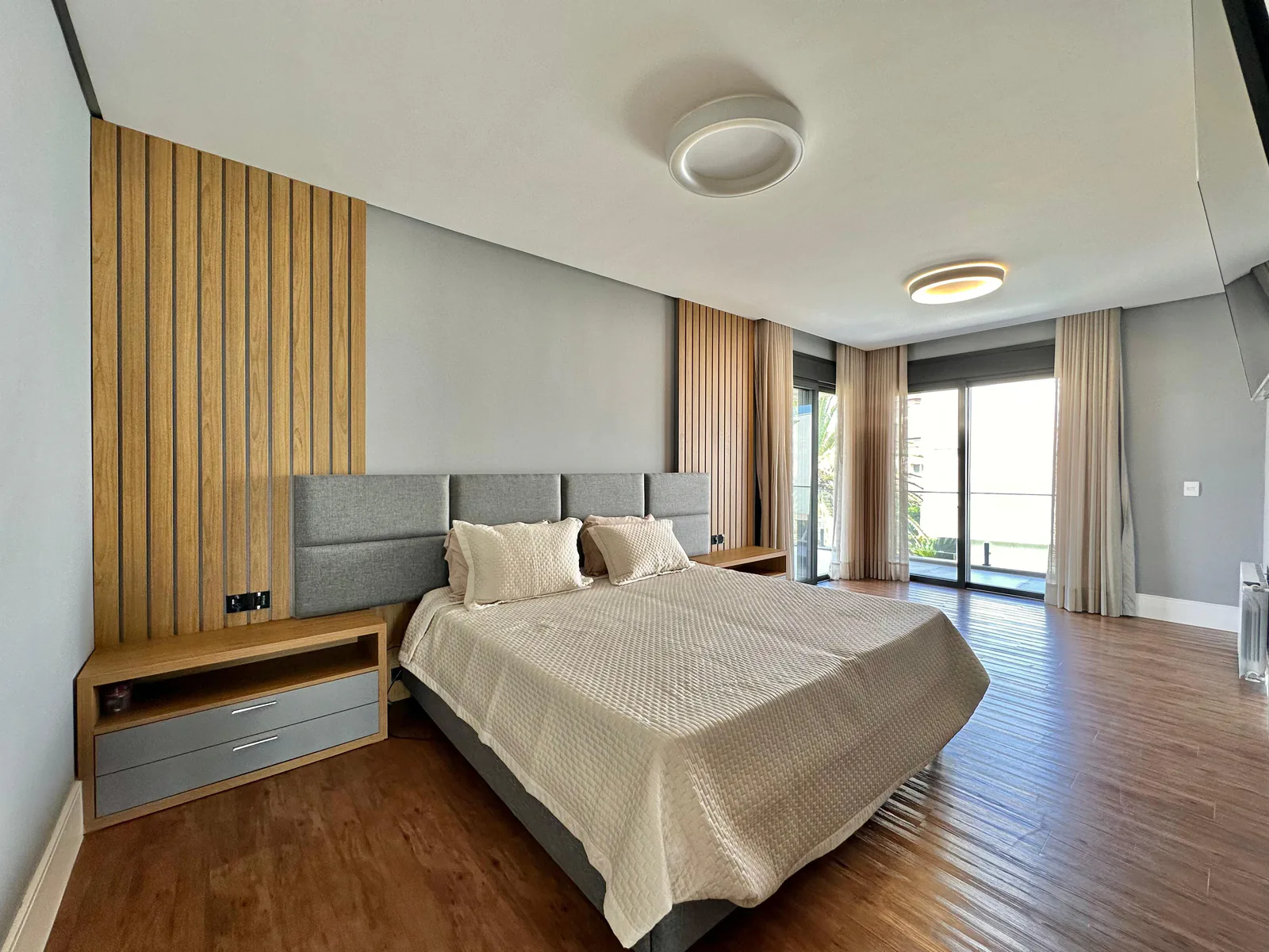 Suíte mobiliada com painel de madeira e abertura para o exterior